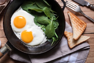 Photo of Delicious fried egg with spinach served on wooden table, flat lay