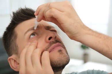 Photo of Man using drops for eyes at home