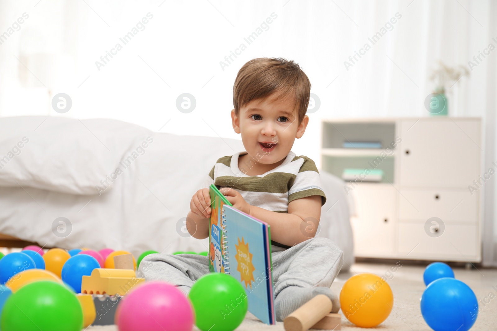 Photo of Cute little child with book playing on floor