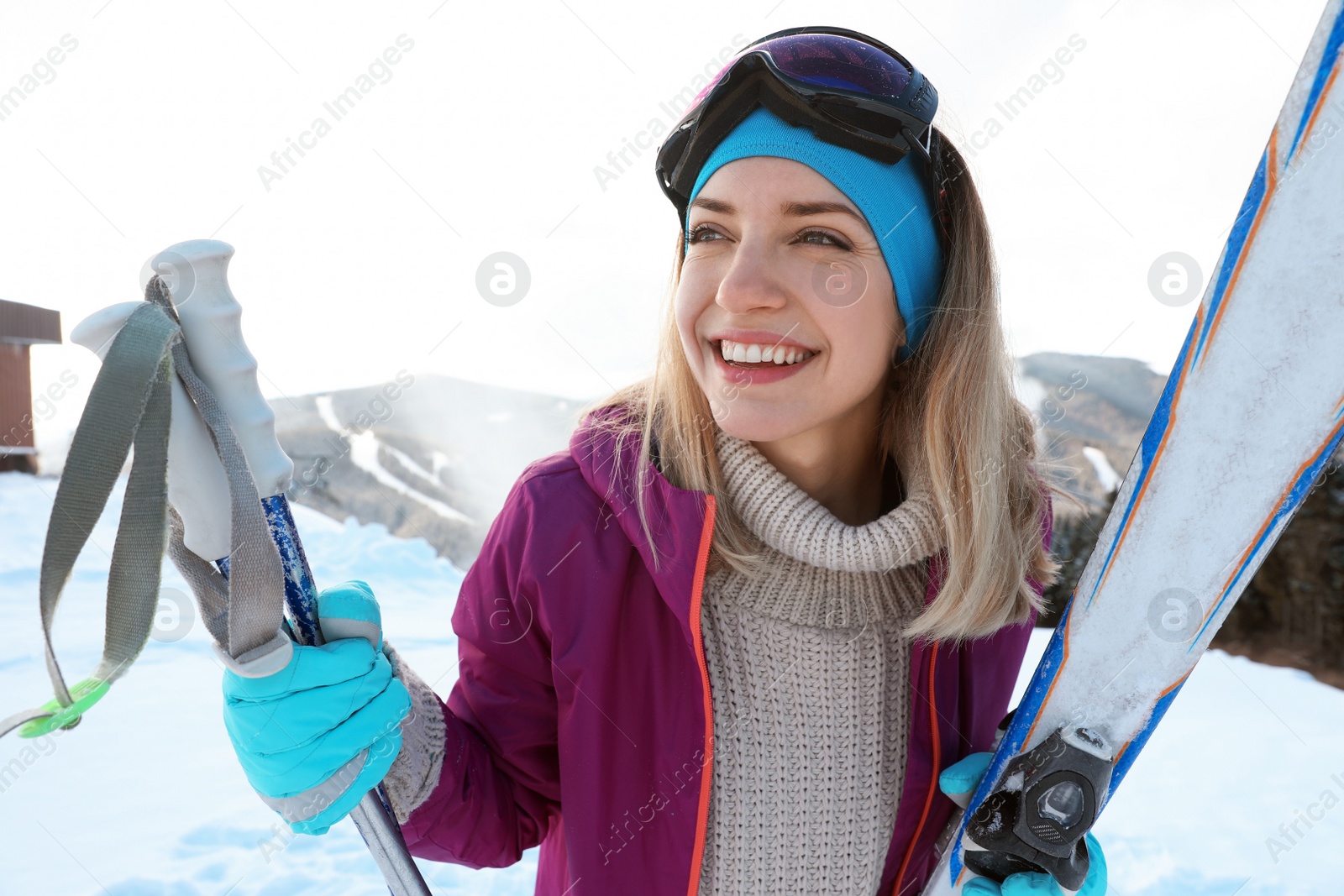 Photo of Happy young woman with ski equipment spending winter vacation in mountains