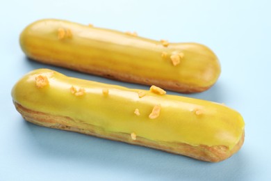 Delicious eclairs covered with glaze on light blue background