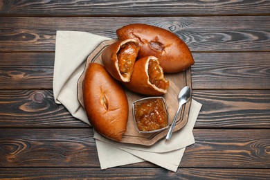 Photo of Delicious baked patties with jam on wooden table, top view