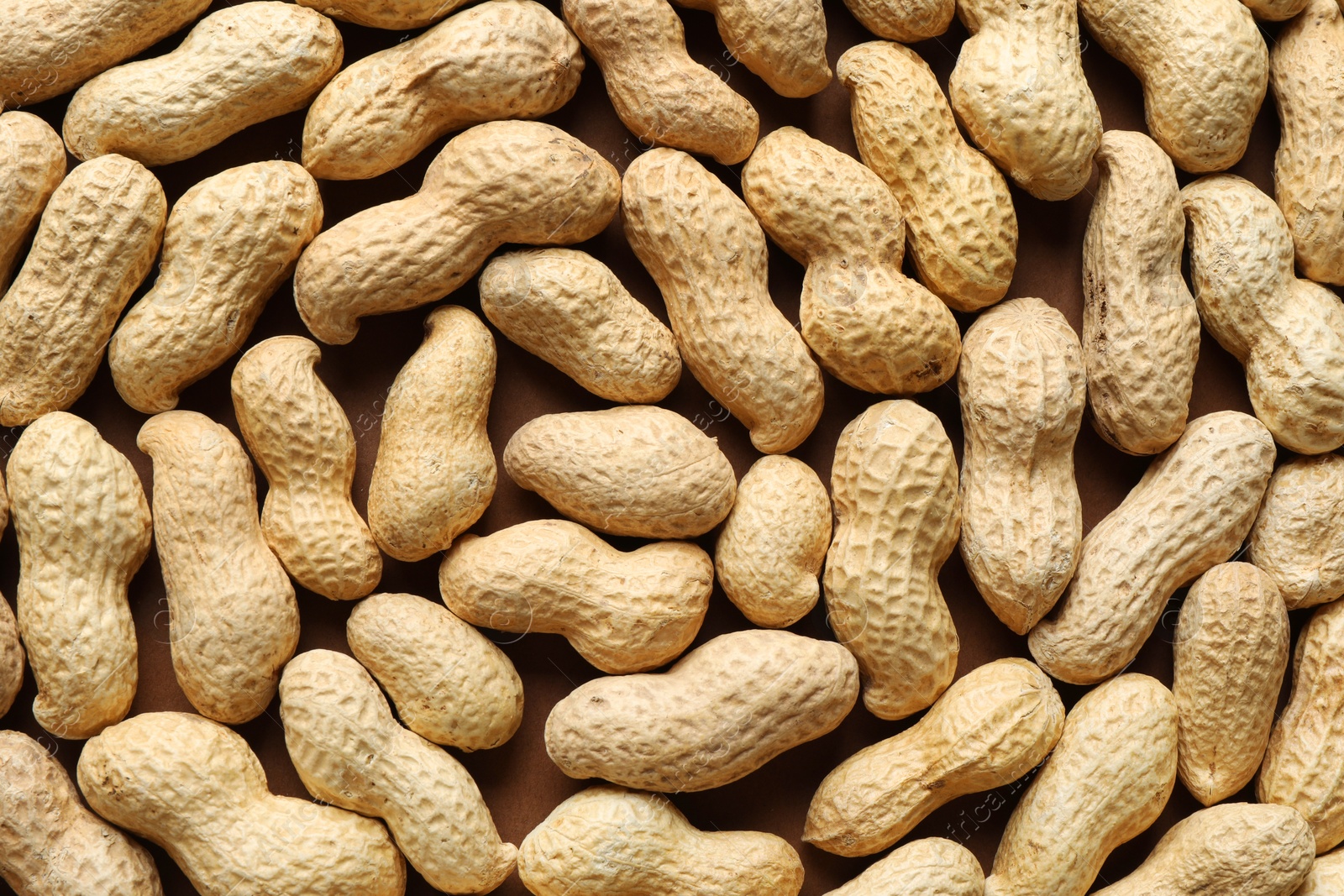 Photo of Many fresh unpeeled peanuts as background, top view