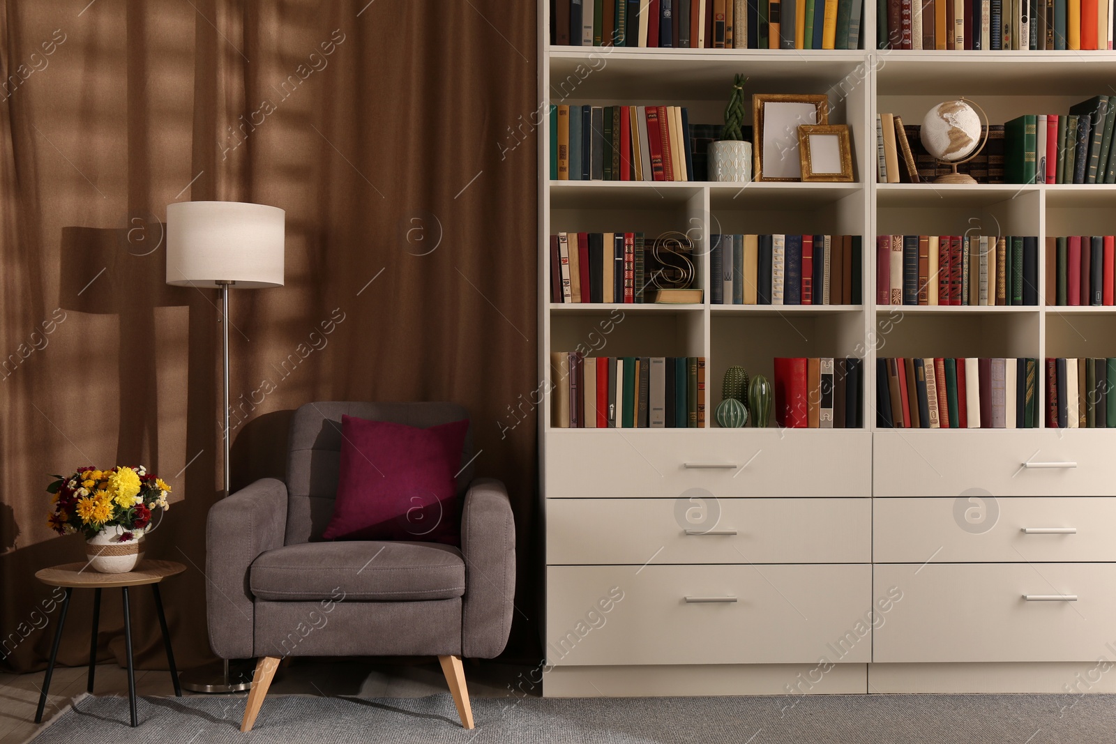 Photo of Cozy home library interior with comfortable armchair, floor lamp and collection of books on shelves