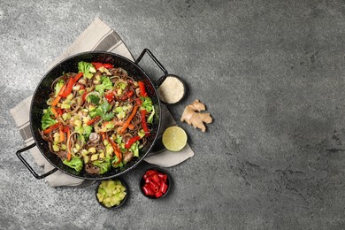 Photo of Wok with noodles, mushrooms, vegetables and other products on grey table, flat lay. Space for text