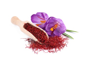Photo of Dried saffron, wooden scoop and crocus flowers on white background