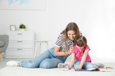 Photo of Young woman and her daughter drawing in living room. Helping to learn