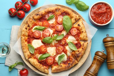 Delicious Margherita pizza and ingredients on light blue wooden table, top view