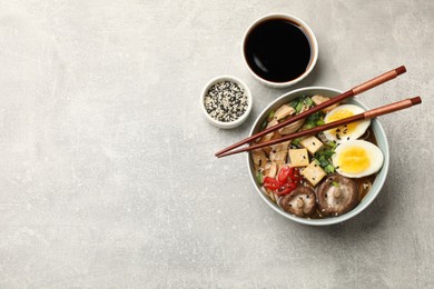 Delicious ramen served on grey table, flat lay with space for text. Noodle soup