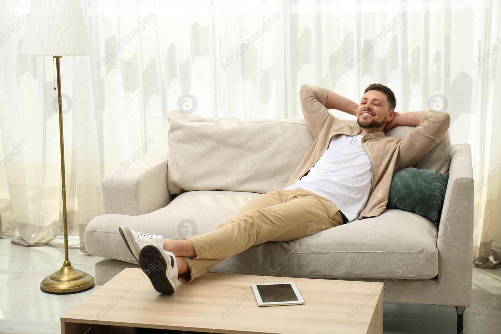 Photo of Handsome man relaxing on sofa at home