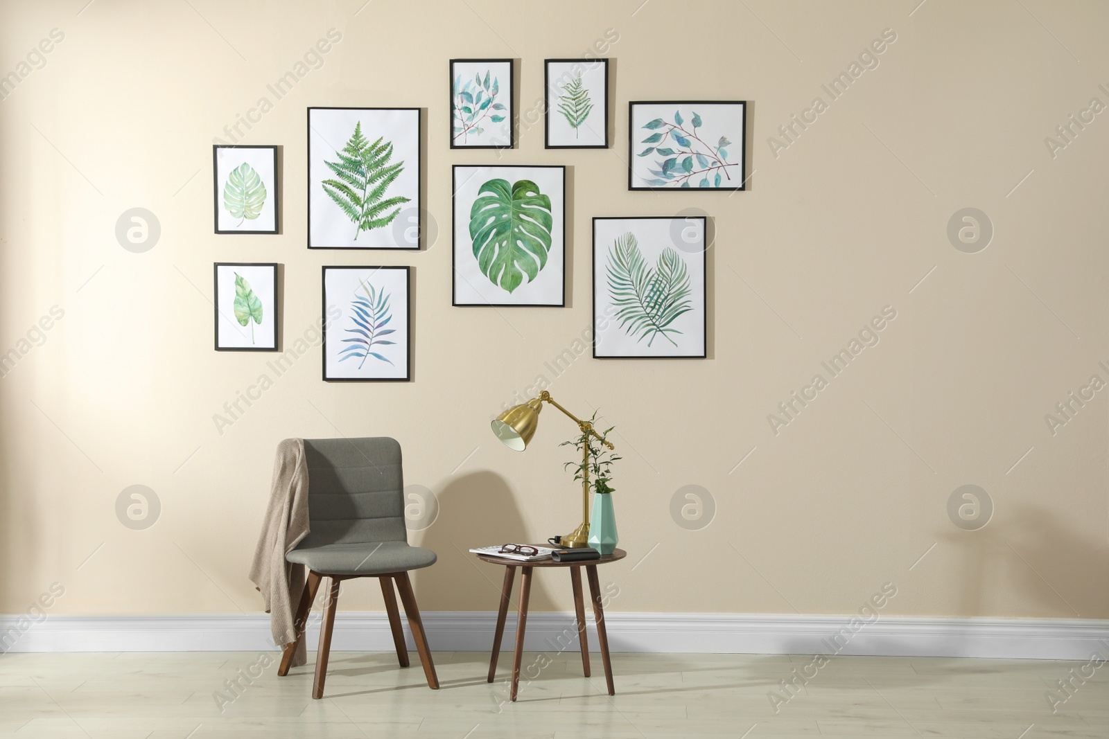 Photo of Beautiful paintings of tropical leaves on beige wall in room interior