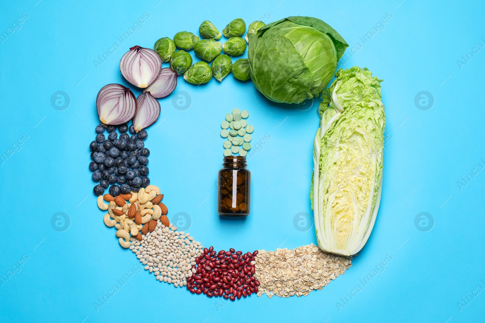 Photo of Bottle with pills and foodstuff on light blue background, flat lay. Prebiotic supplements