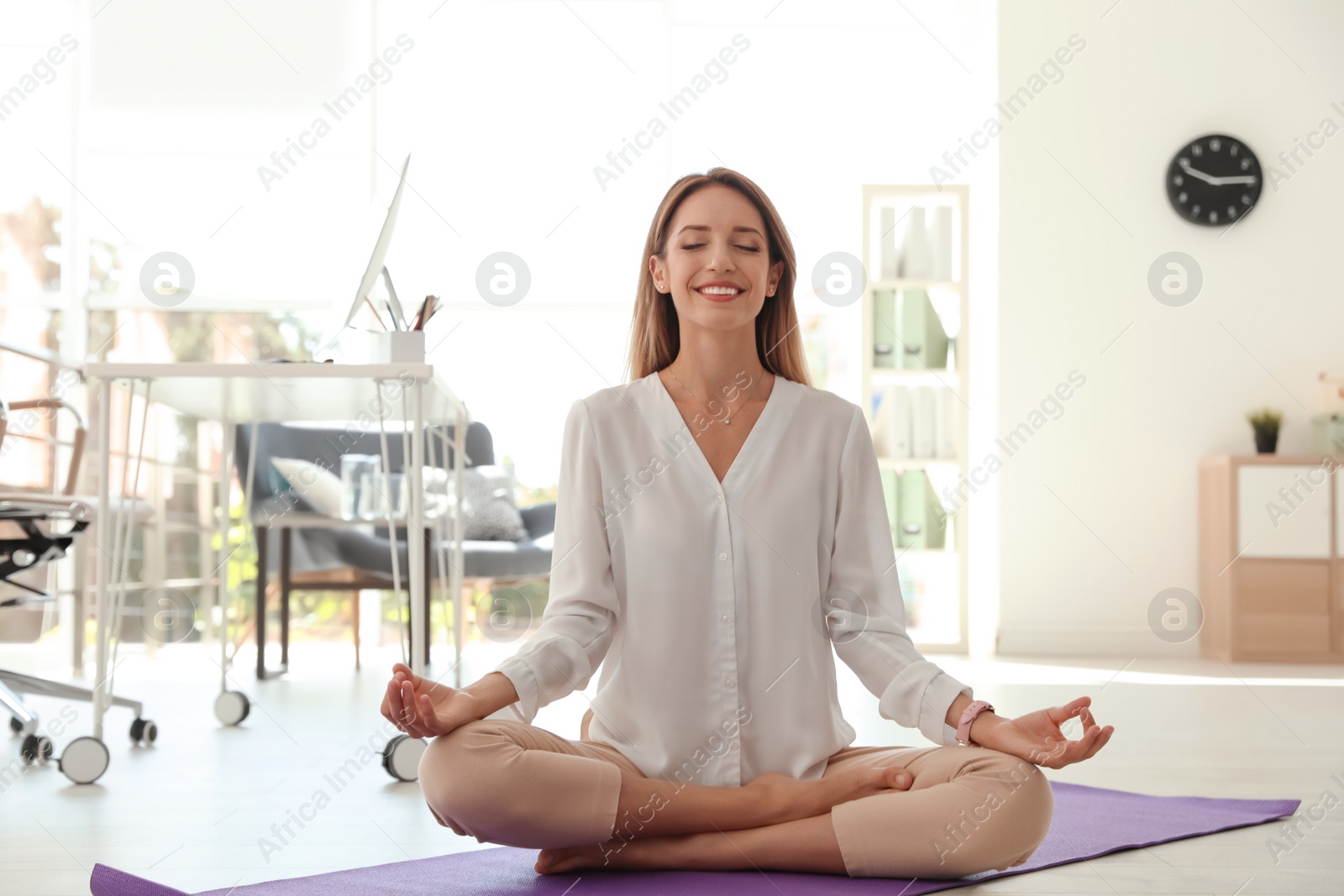 Photo of Young businessman doing yoga exercises in office. Workplace fitness