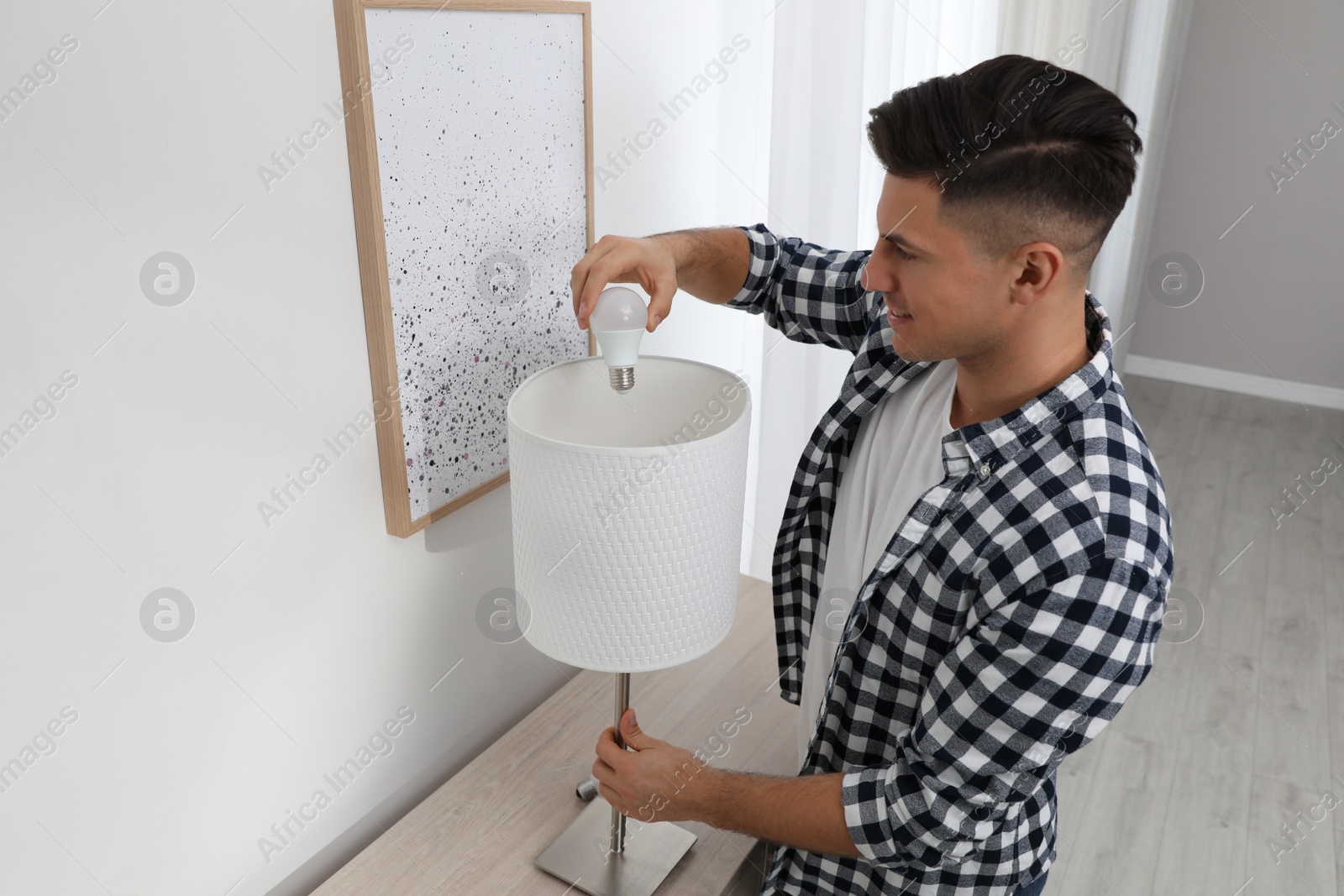 Photo of Man changing light bulb in lamp at home