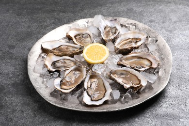 Photo of Delicious fresh oysters with lemon on grey table