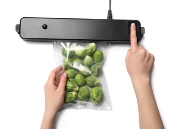 Photo of Woman using sealer for vacuum packingBrussels sprouts on white background, top view