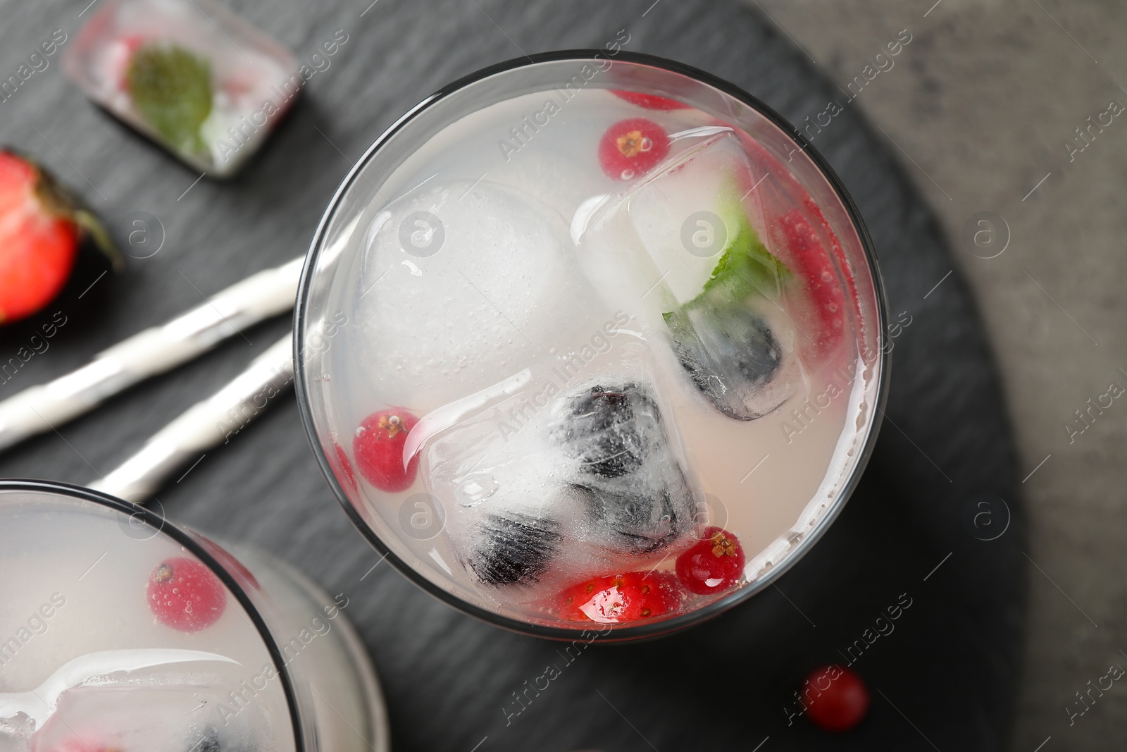 Photo of Glasses of refreshing drink with ice cubes and berries on grey table, top view