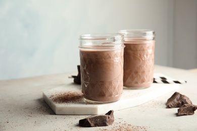 Photo of Jars with tasty chocolate milk on table. Dairy drink