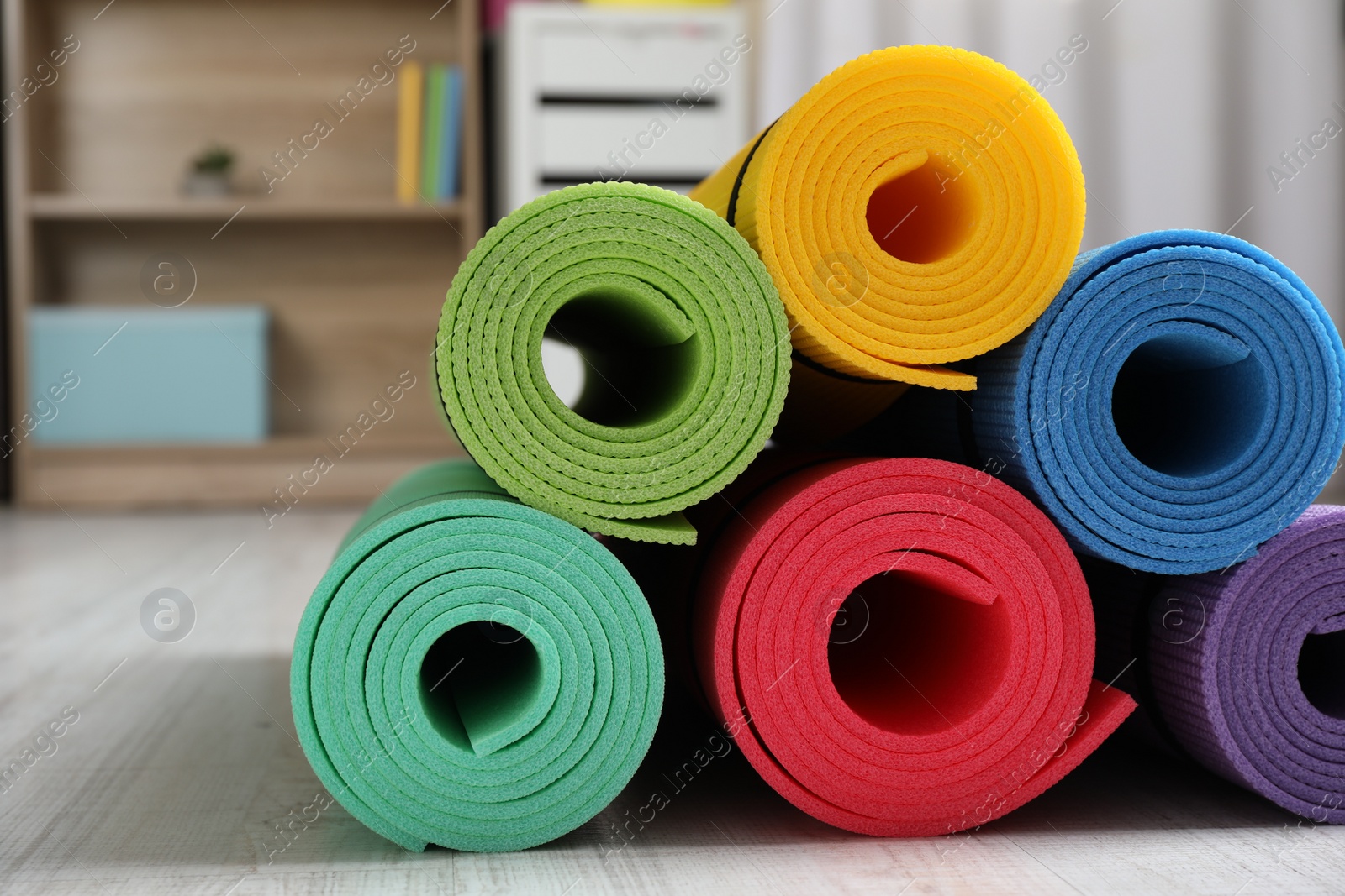 Photo of Bright rolled camping mats on white wooden floor indoors