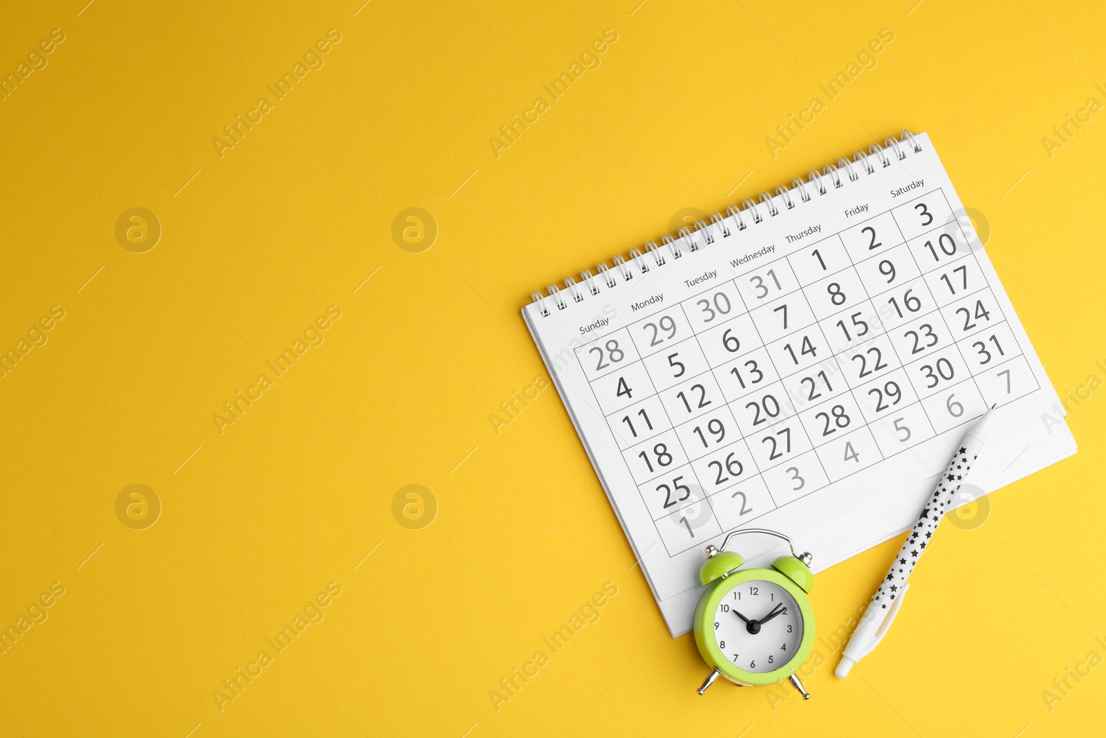 Photo of Calendar, pen and alarm clock on yellow background, flat lay. Space for text
