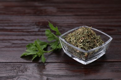 Photo of Dried aromatic parsley and fresh leaves on wooden table, space for text
