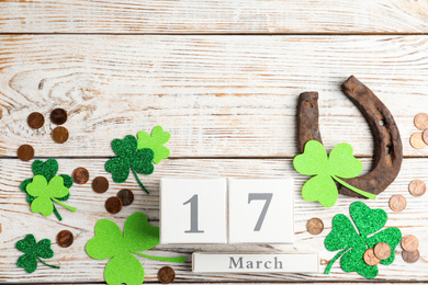 Flat lay composition with horseshoe and block calendar on white wooden background, space for text. St. Patrick's Day celebration