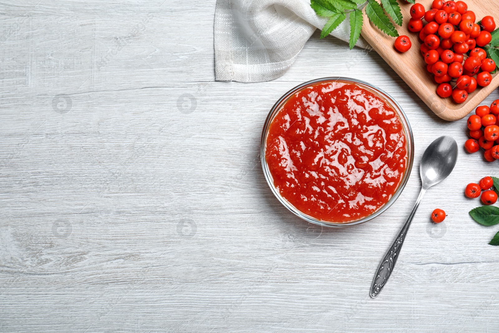 Photo of Flat lay composition with delicious rowan jam on white wooden table. Space for text