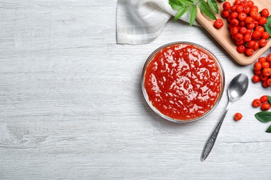 Flat lay composition with delicious rowan jam on white wooden table. Space for text