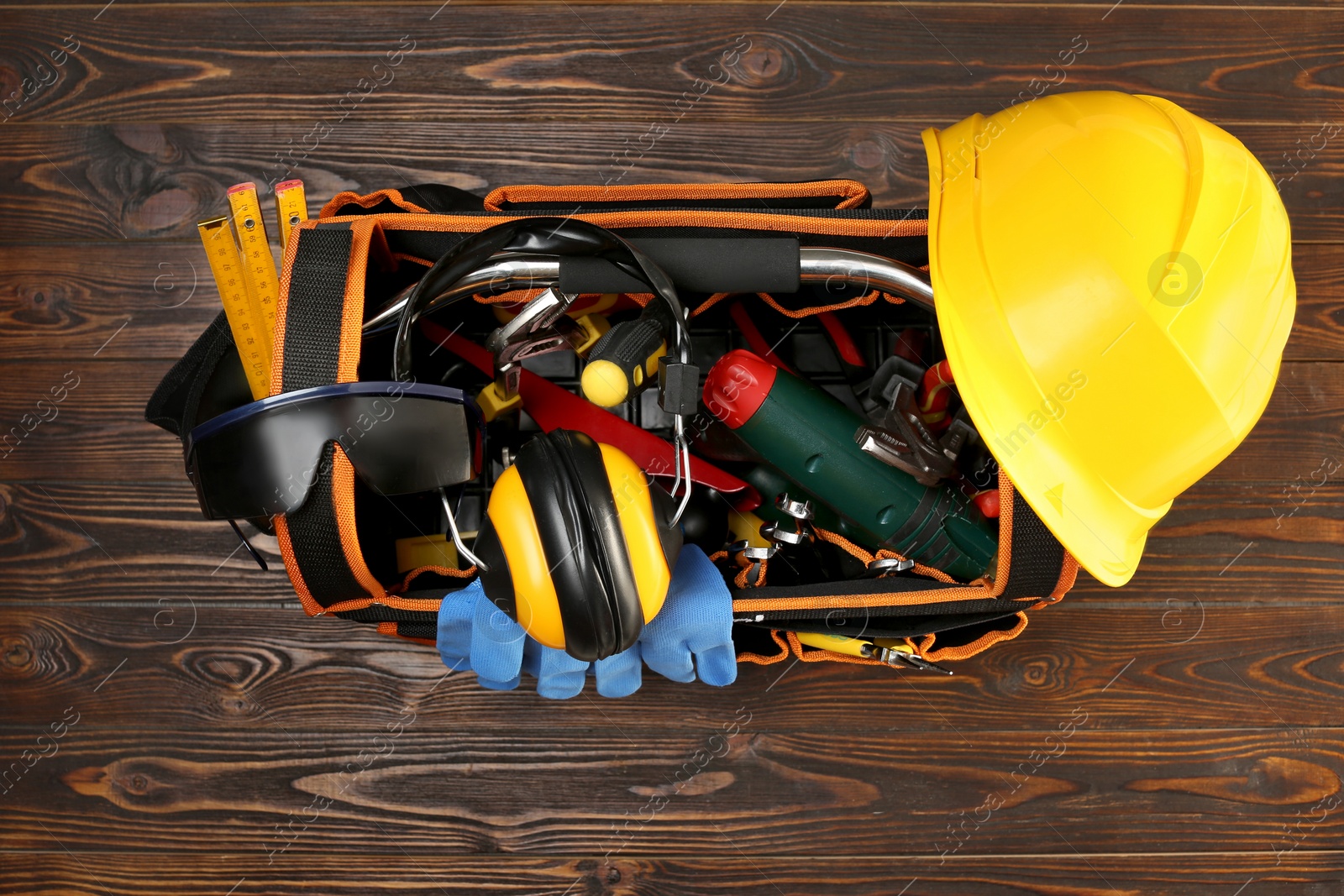 Photo of Bag with different tools on wooden table, top view