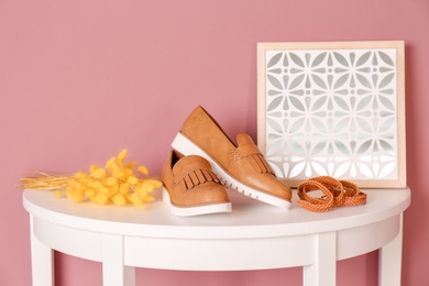 Stylish female shoes and belt on table