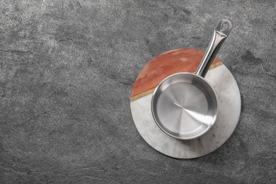 Photo of Empty steel saucepan and board on grey table, top view. Space for text