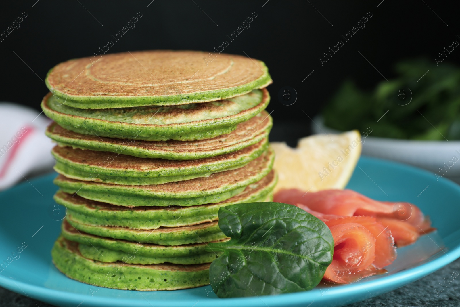 Photo of Tasty spinach pancakes with salmon on table, closeup