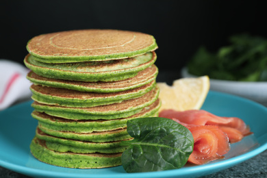 Tasty spinach pancakes with salmon on table, closeup