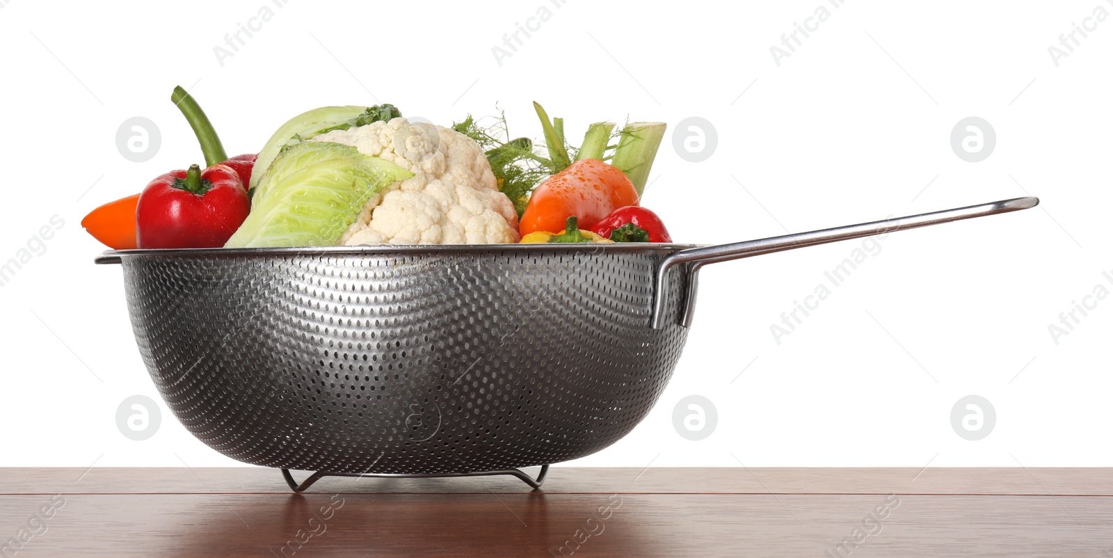 Photo of Metal colander with different vegetables on wooden table against white background