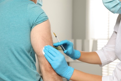 Doctor giving injection to patient in hospital, closeup. Vaccination day