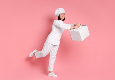 Happy confectioner with cake box on pink background