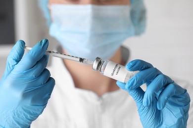 Nurse filling syringe with monkeypox vaccine from glass vial in hospital, closeup