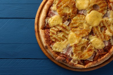 Photo of Delicious pineapple pizza on blue wooden table, top view. Space for text