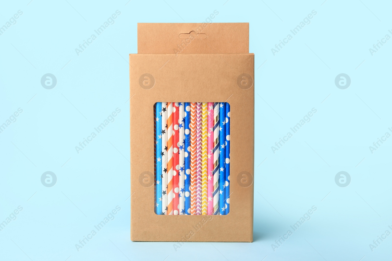 Photo of Box with many paper drinking straws on light blue background