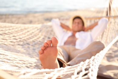 Photo of Man relaxing in hammock outdoors, focus on leg