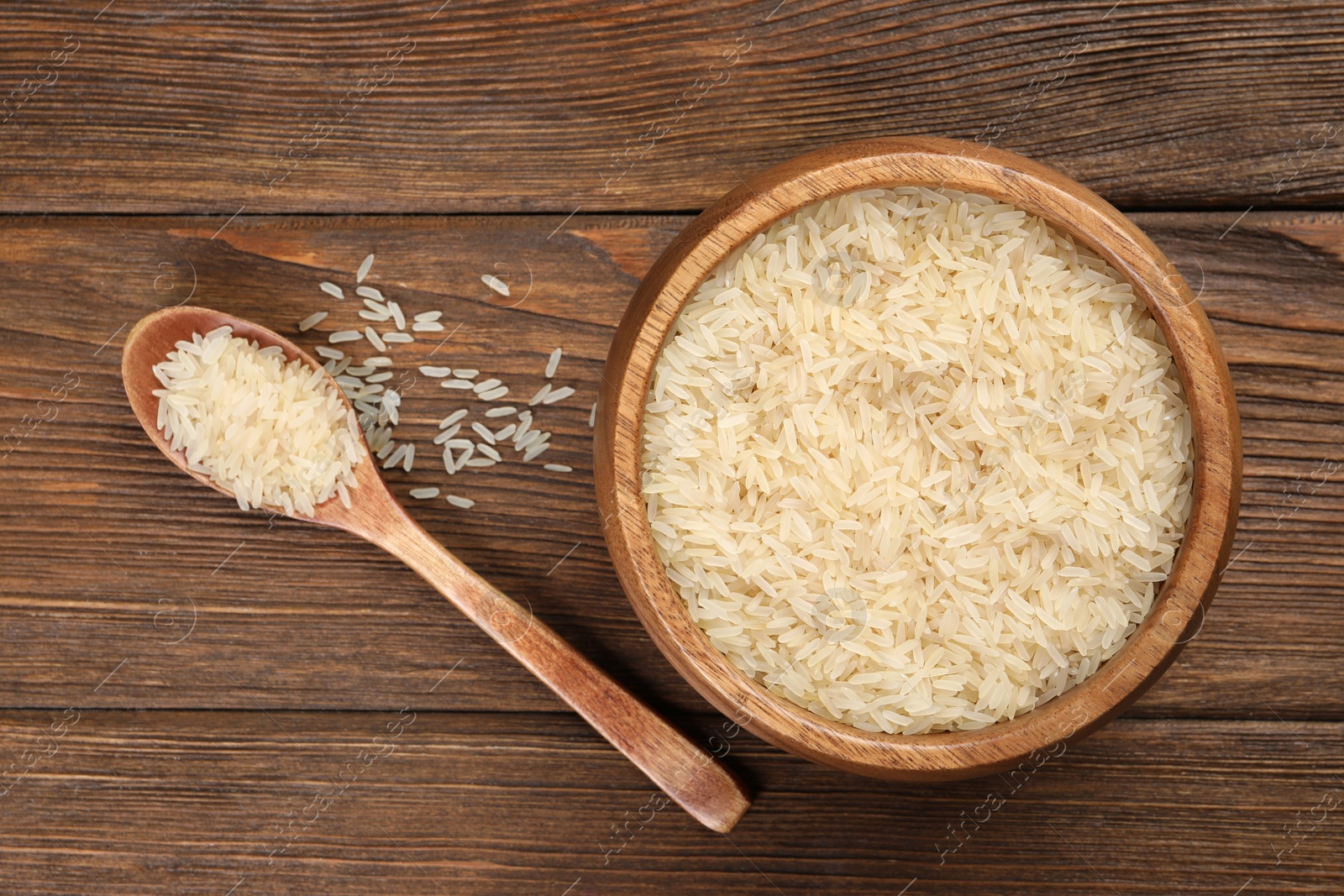 Photo of Bowl and spoon with white rice on wooden table, flat lay