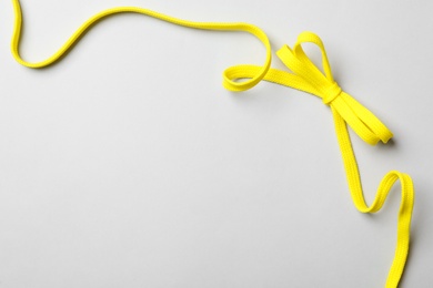 Yellow shoelace on light background, top view. Space for text