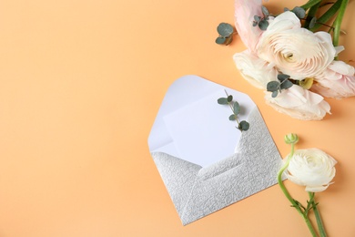 Flat lay composition with beautiful ranunculus flowers and card in envelope on color background