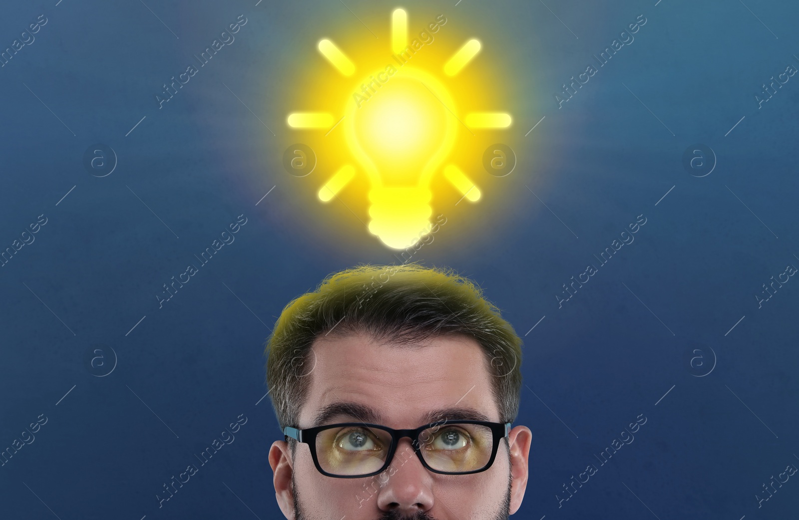 Image of Idea generation. Man looking at illustration of glowing light bulb over him on dark blue background