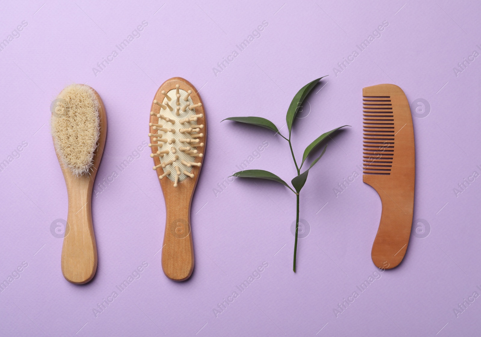 Photo of Wooden brushes and plant on violet background, flat lay. Conscious consumption