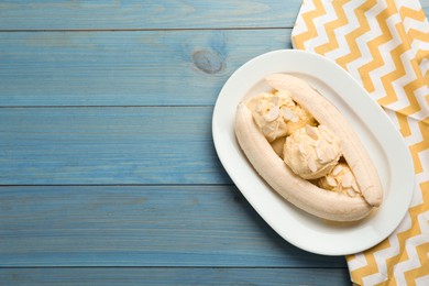Delicious banana split ice cream on light blue wooden table, top view. Space for text
