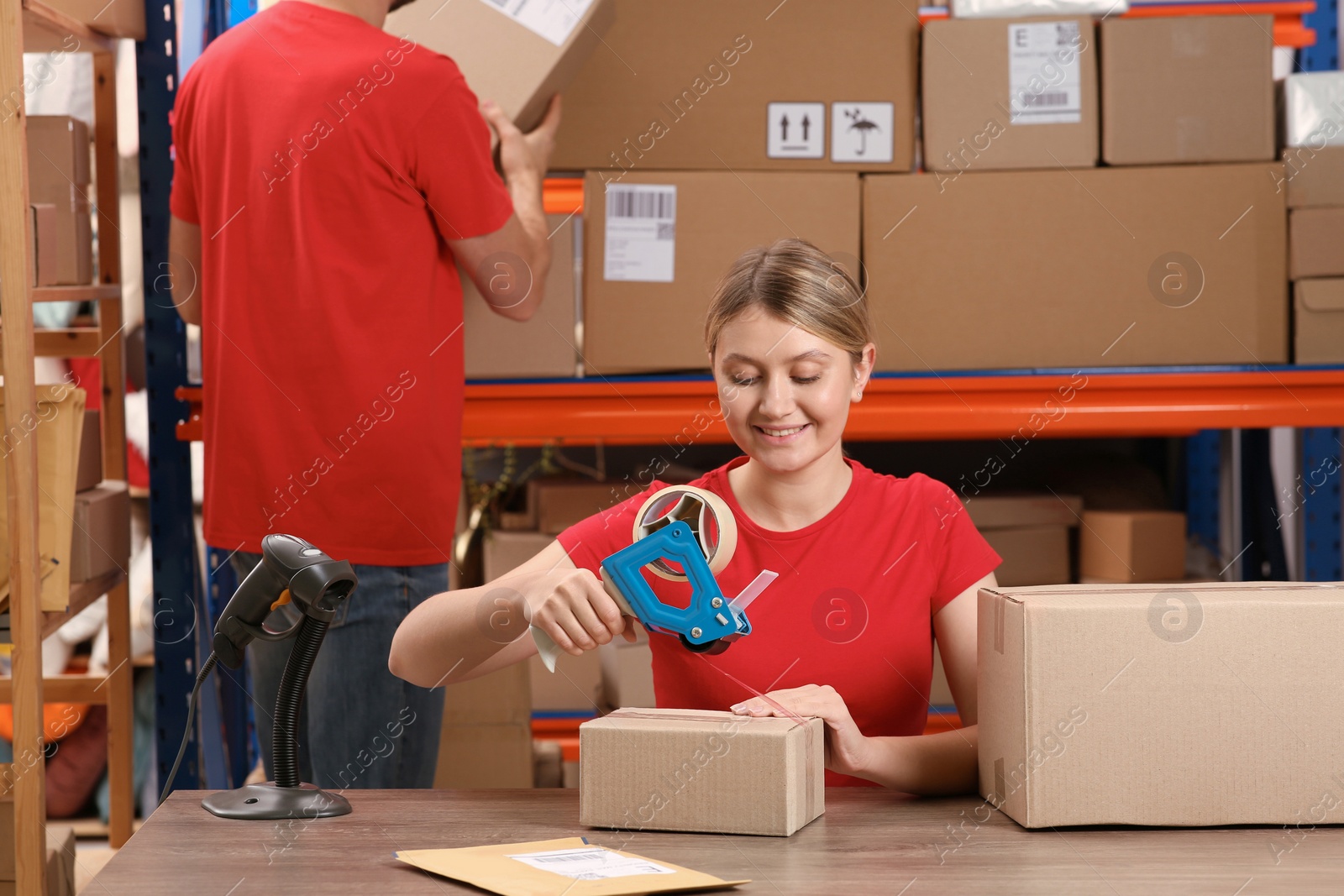 Photo of Post office worker packing parcel at counter indoors