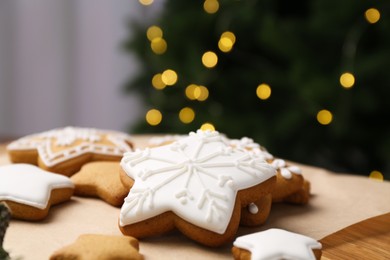 Photo of Decorated cookies on table against blurred Christmas lights, closeup