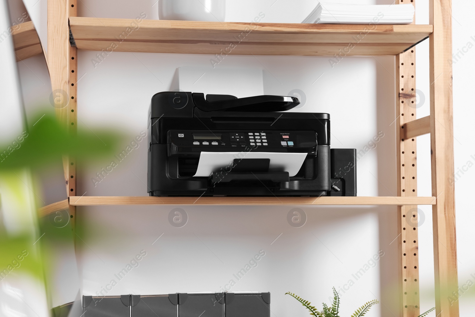 Photo of Modern printer with paper on wooden shelf in home office