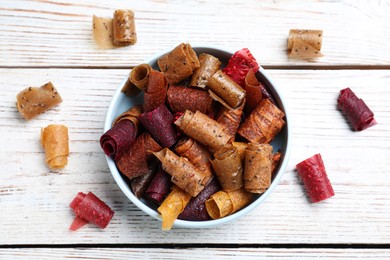 Photo of Delicious fruit leather rolls on white wooden table, flat lay